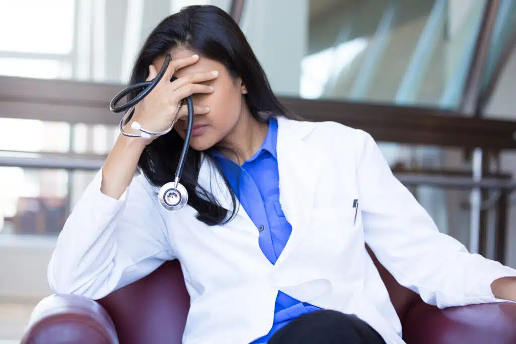 Stressed physician holding her hand over her face